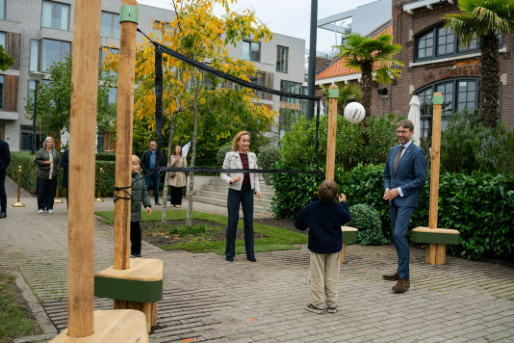 Heleen Aarts (Amvest) en wethouder Steven van Weyenberg testen samen met omwonende kinderen het volleybalnet bij de opening van Amfi, het jubileumcadeau van Amvest aan de inwoners van de stad.